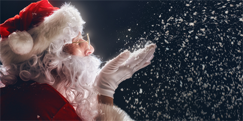 A close up of Santa gently blowing snow from cupped hands.